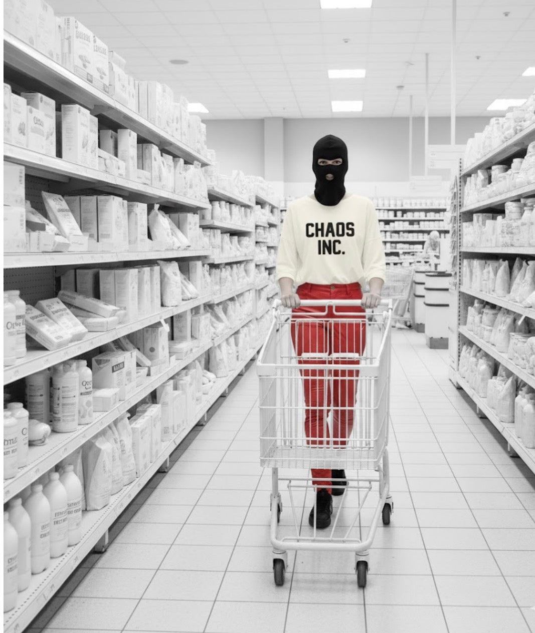 Person in a supermarket aisle with 'Chaos Inc.' shirt and red pants.